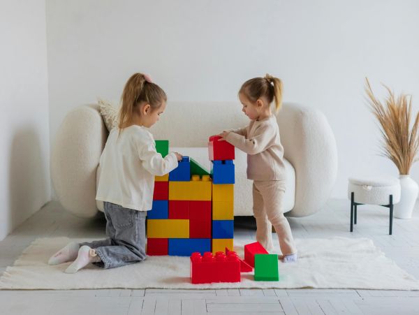 Zwei Kinder in Beigem Umfeld Spielen mit bunten Klemmbausteinen