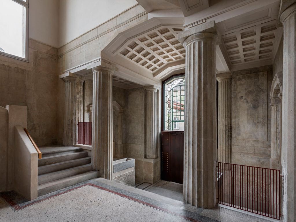 Eingang zu einem großen Gebäude mit majestätischen Säulen und einer großen Treppe, die zur 1. Etage führt