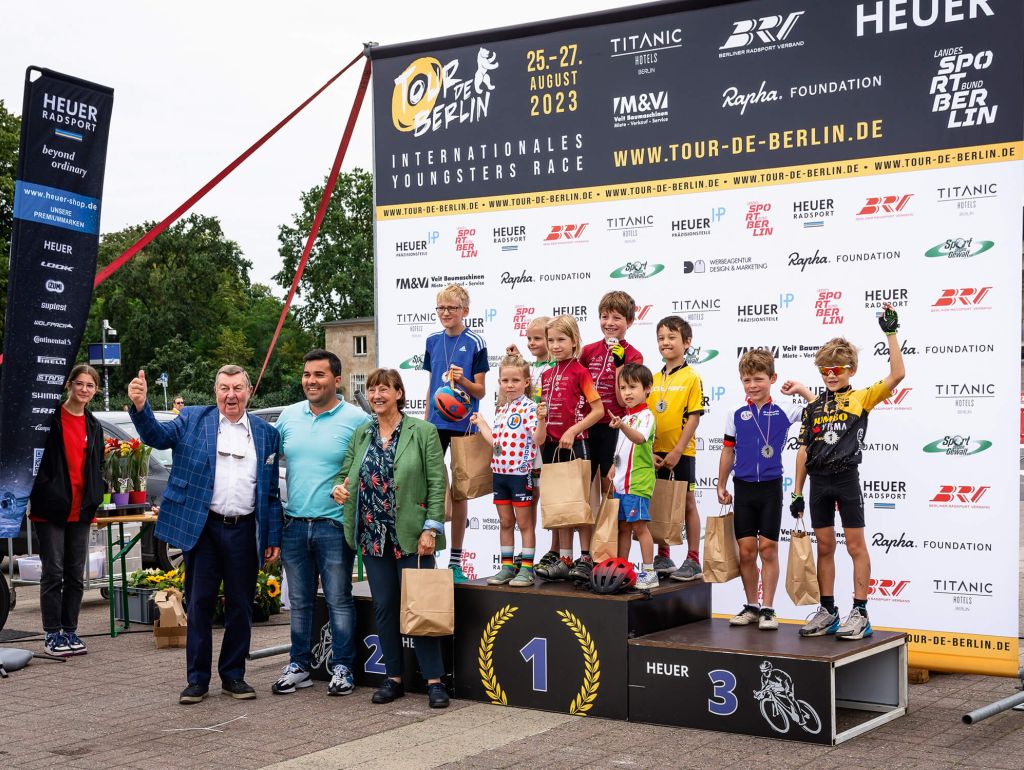 Kinder posieren nach einem Fahrradrennen auf dem Siegerpodest