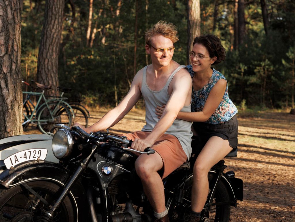 ein Pärchen sitzt auf einem Oldtimer Motorrad im Wald