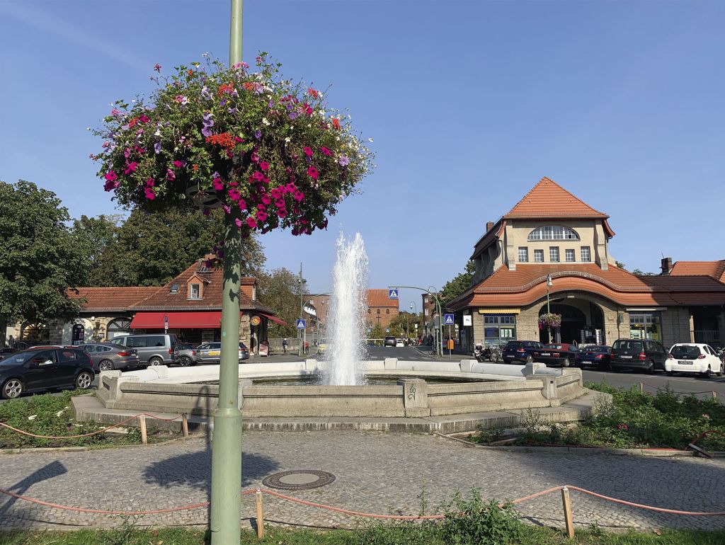 ein Platz mit springbrunnen an den Laternen hängen Blumengestecke