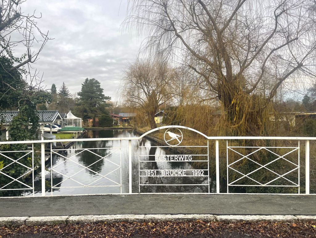 Blick von Brücke über ein Kanal mit Bäumen un Häuser im Hintergrund