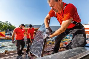 3 Männer bauen eine Solarzelle auf das Dach eines Hauses